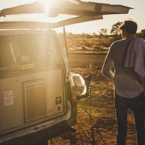 Homme dans nature cuisine devant son van aménagé en autonomie